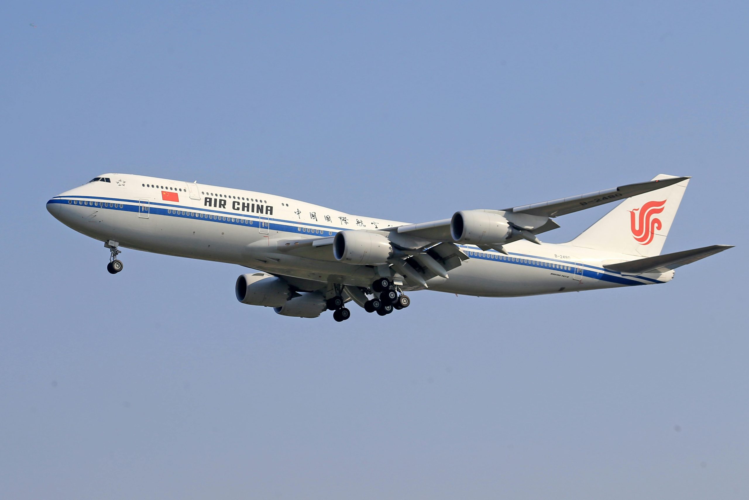 Air China Boeing 747 flying under a clear blue sky, showcasing airline transportation.