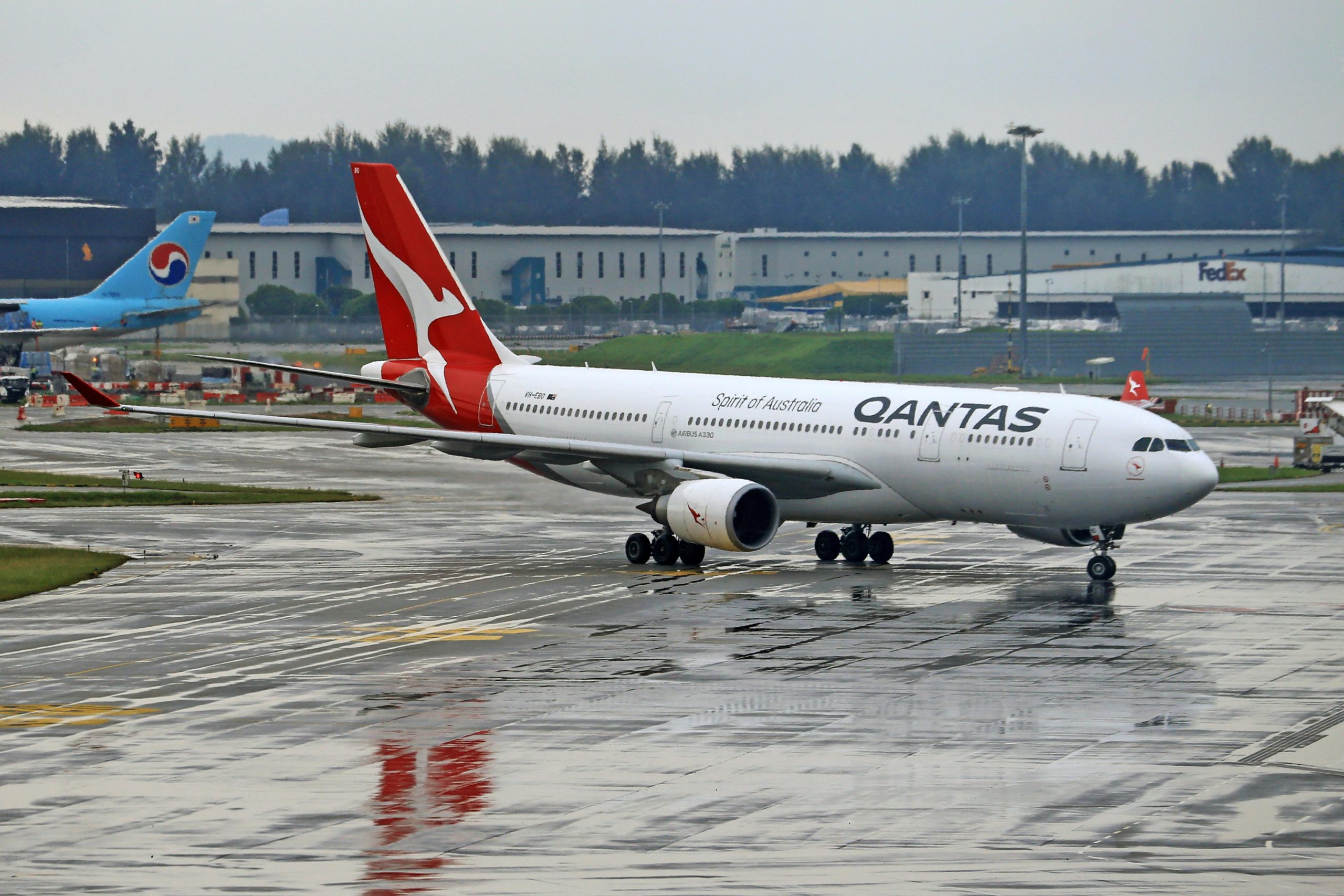 Qantas Airbus A330 taxiing on a rainy airport runway. Ideal for travel and aviation themes.