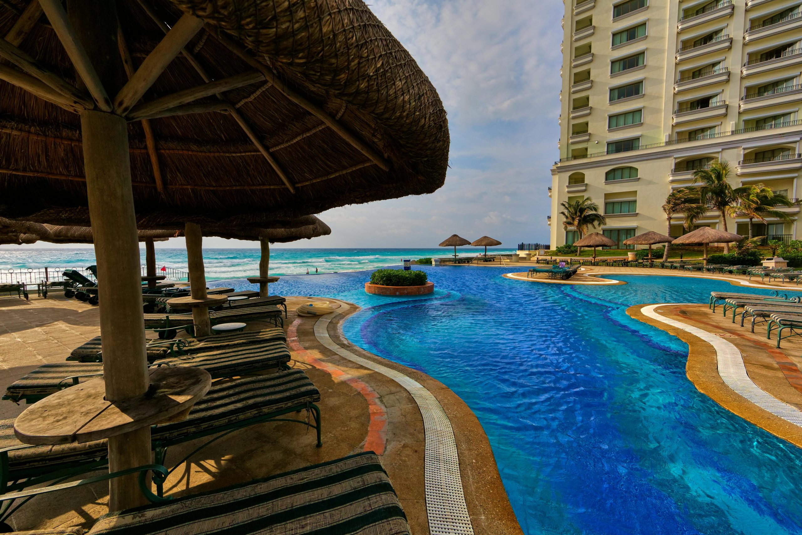 A tropical resort with a luxurious poolside overlooking the ocean, perfect for relaxation and leisure.